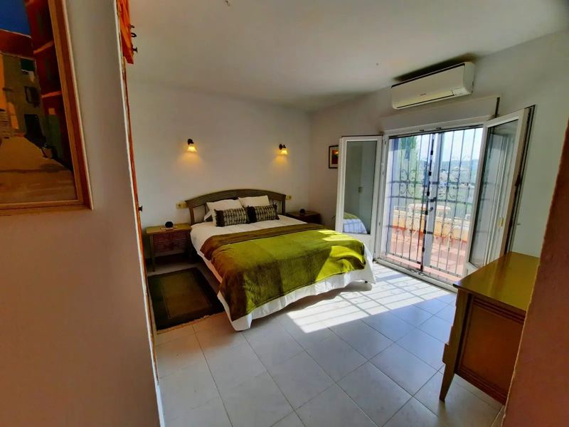 Bedroom with green bedspread, air conditioning and terrace door