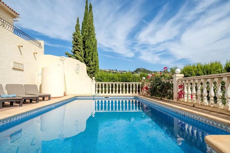 Pool with white balustrade and cypress trees