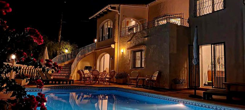 The pool and villa lit up at night